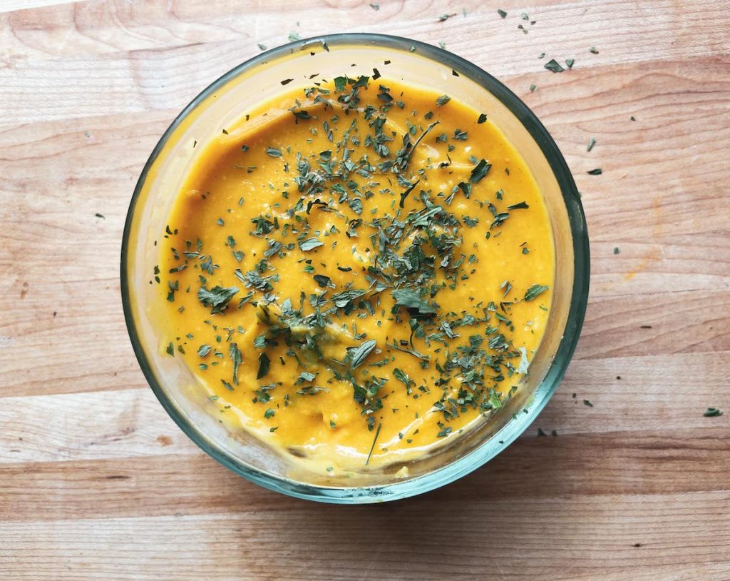 glass bowl with soup in it and parsley on top