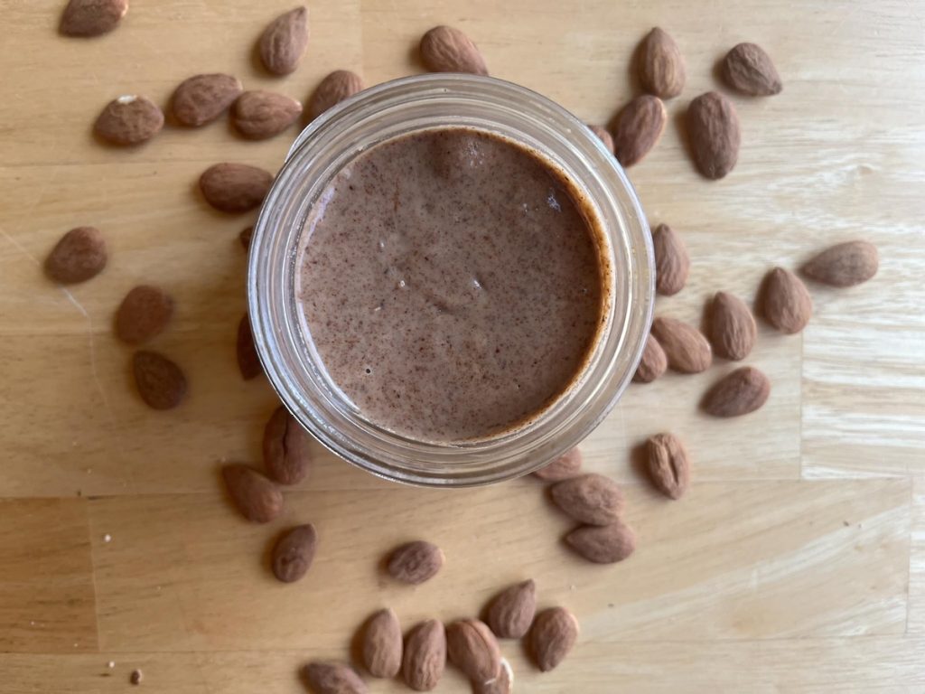 almond butter on a counter with whole almonds scattered around
