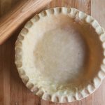 sourdough pie crust ready for baking with rolling pin in upper left corner