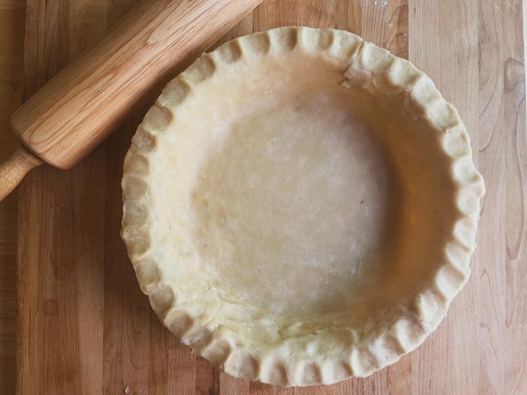 sourdough pie crust ready for baking with rolling pin in upper left corner