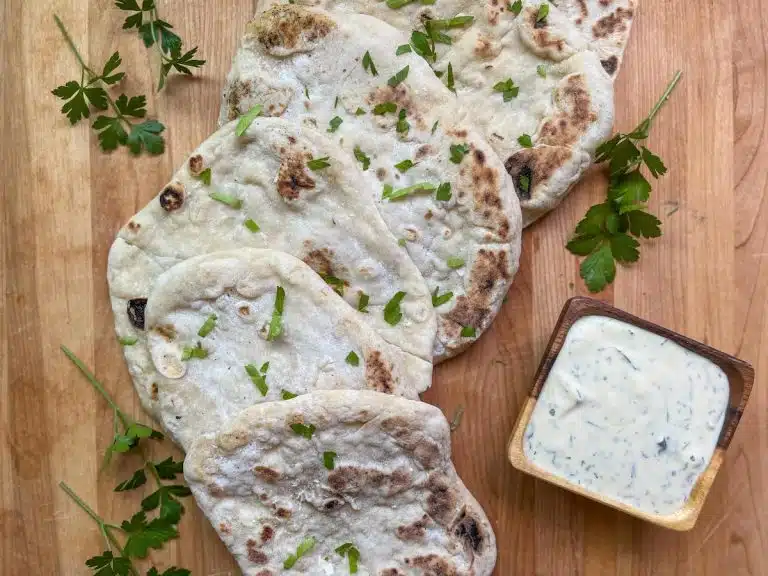 sourdough flatbread spread out on a cutting board with parsley and ranch dip