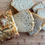 sandwich load of bread on left with slices on the right against a wooden background